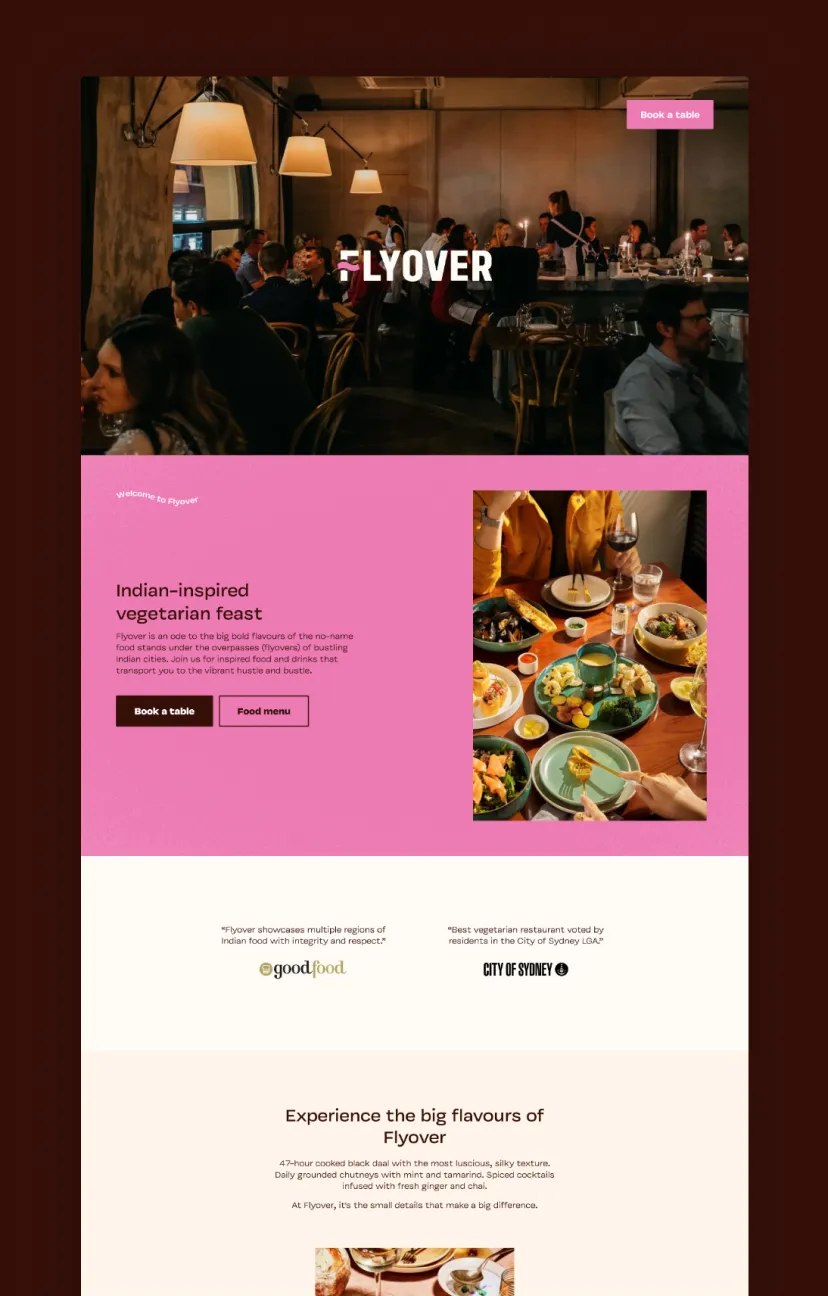 Busy restaurant interior with diners and warm lighting, featuring Flyover restaurant branding, a pink section highlighting Indian-inspired vegetarian dishes with a table set with colorful food and wine.
